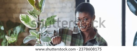 Concept of wellbeing, relaxation, work life balance, simple pleasures. Beautiful smiling plus size African American woman is doing home gardening, repotting, taking care about plants. Banner
