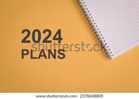2024 Plans with notepad. Top view. On yellow background.