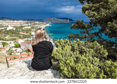 A girl on the background of a view from the Genoese fortress to the Sudak Bay. Sudak May 2021 Royalty-Free Stock Photo #2378612225