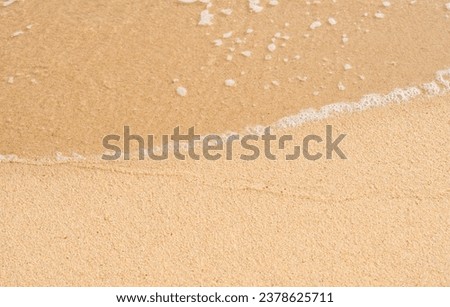 Sea beach waves with foam on sand texture surface background. Copy space of summer vacation and holiday business travel concept. Sand beach banner for cosmetic background