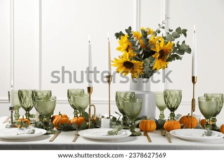 Beautiful autumn table setting with bouquet indoors. Plates, cutlery, glasses and floral decor