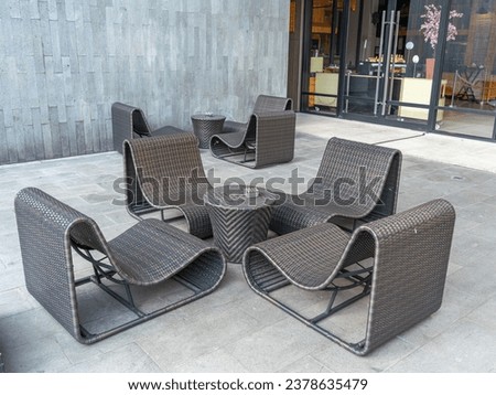 Two sets of rattan patio furniture each consisting of four chairs and a small cylindrical coffee table.