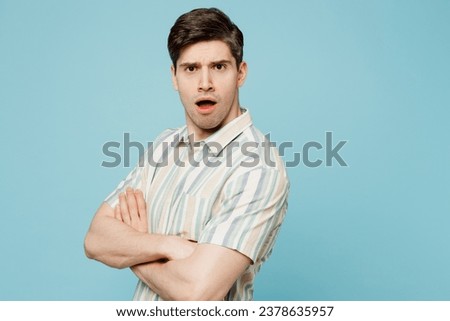 Side view young sad shocked mad man he wears striped shirt casual clothes hold hands crossed folded look camera isolated on plain pastel light blue cyan background studio portrait. Lifestyle concept Royalty-Free Stock Photo #2378635957