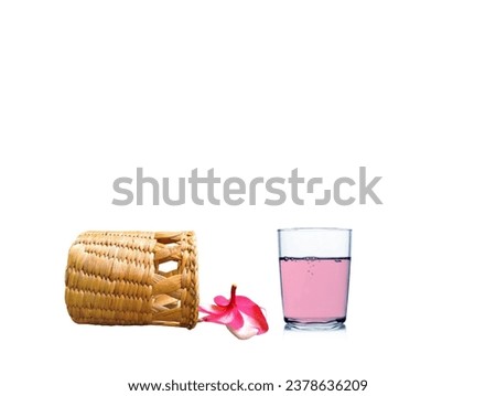 The white background in the picture has a light brown woven basket and pink and white frangipani flowers and water in a pink glass.