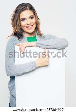 portrait of smiling woman holding white blank sign board. female model toothy smiling. thumb up show young woman.