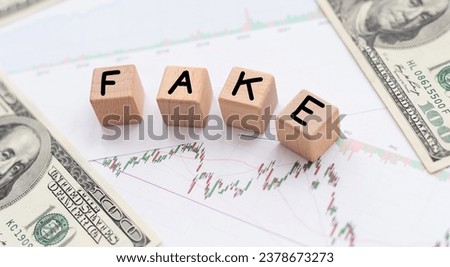 The word 'fake' written on wooden blocks, a man sitting in front of his desk with a pen and notebook on it