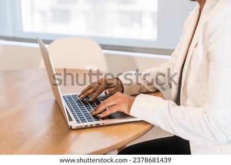 Close-up of the hands of a businesswoman working with laptop on a wooden table