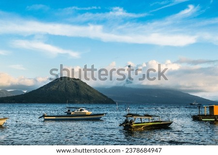 Majestic Maitara, Tidore Mountains, Ternate Beach: A breathtaking shot capturing the grandeur of these iconic peaks under a clear blue sky, framed by fluffy white clouds. Nature's beauty on display.