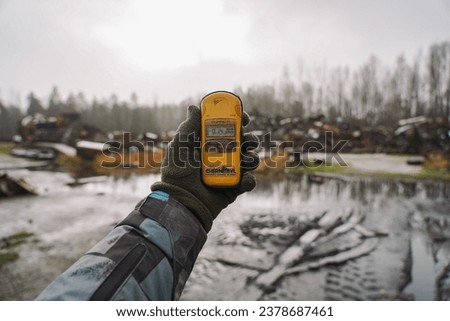 Dosimeter in hand on background museum of special equipment that helped cleaning Chernobyl nuclear power plant after explosion. Radiation sign