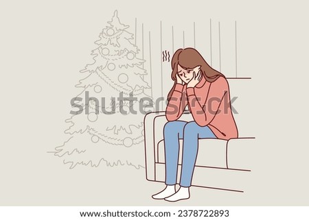 Woman is sitting on sofa near christmas tree and is sad because of loneliness and lack of friends during new year holidays. Christmas melancholy in girl in need of psychological support