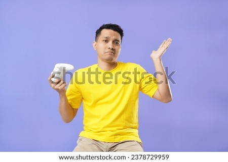 Sadness gamer man holding joystick. He lose in the game. Missed the chance to become a champion in tournament. Isolated on purple background