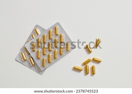 2 blister packs and yellow capsules displayed on a white background. Antibiotic pill sample. Copy space for medication advertising. Royalty-Free Stock Photo #2378745523