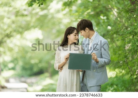 A loving couple are taking wedding photos with green boards outdoors for their wedding.