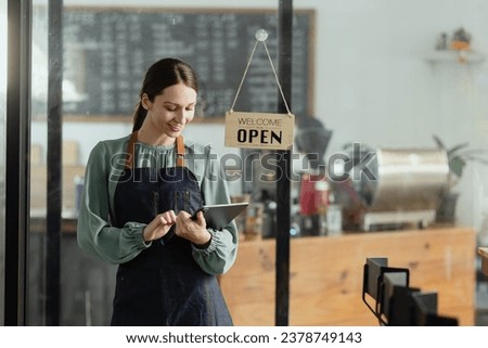 Happy young female owner standing with open sign at coffee shop, Smiling small business owner showing open sign. 
