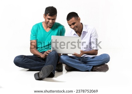 Two male Indian friends using a tablet PC. Isolated on White Background.