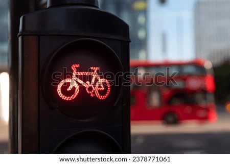 A red cycle lane traffic stop signal at a junction in a busy London city street with a double decker bus passing in the background. Royalty-Free Stock Photo #2378771061