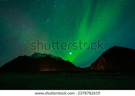 Awesome Northern lights over the snowy mountains, in Lofoten islands, Norway.