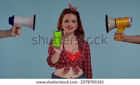 Young woman. She looks at the camera and smiles. In front of her, she holds a phone with a green screen. On both sides she is pointed loudspeakers, horn. Here may be your advertisement. HDR BT2020 HLG