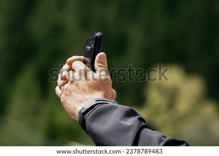 
A man's hand is holding a phone. He is on the phone, sending a message or taking a photo.