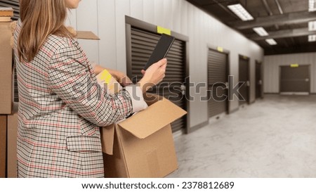 Storage units. Woman with box in warehouse building. Girl rents storage room. Place for safekeeping unnecessary things. Corridor with doors in storage units. Crow in warehouse rooms are closed. Royalty-Free Stock Photo #2378812689