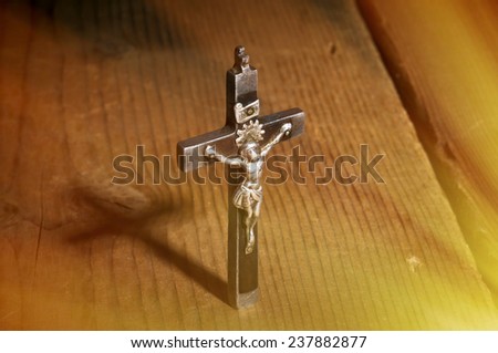 Old metal and wooden Crucifix with shadow on wooden background. With special lighting effect.