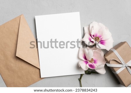 Blank greeting card mockup with gift box, envelope and flowers, card with copy space