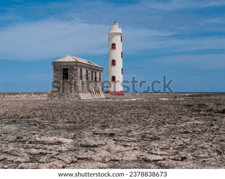 Old lighthouse and lighthouse keeper from the back side on Boka Spelonk at the East side of Bonaire. The house of the lighthouse keeper is a ruin. There are clouds in the air. The photo is horizontal.