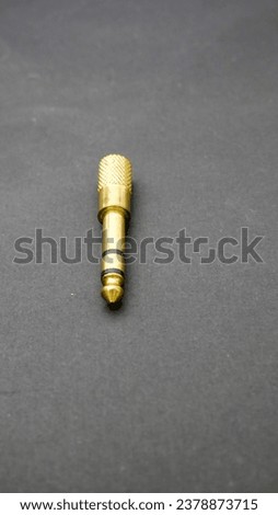 Converter Audio Jack from 3.5 mm to 6.5 mm gold color in black background. Surabaya, East Java, Indonesia. January 07, 2023