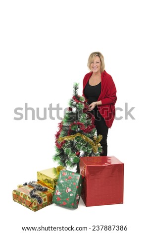 Middle aged woman standing next to a christmas tree against a white background