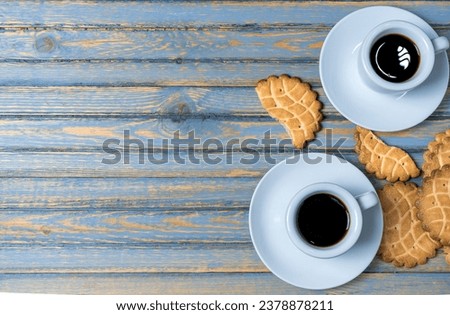 Two coffee cups with coffee on a wooden table and with cookies. 