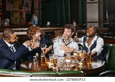 happy multiethnic men pointing at friend in bar, male friends during bachelor party in bar Royalty-Free Stock Photo #2378883913