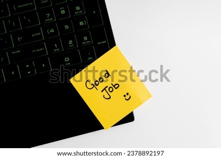 Top view of words good job written on sticky note on keyboard over wooden background.