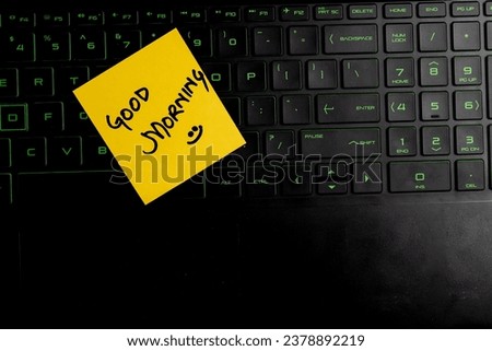 Top view of words good morning written on sticky note on keyboard over wooden background.
