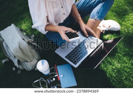 Cropped female blogger using cellphone and laptop technologies for sharing media files, skilled IT professional with mobile phone and netbook computer browsing website for making online booking