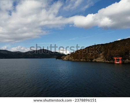 Mount Fuji viewd from Lake Ashi's calm water, a red Torii in the frame