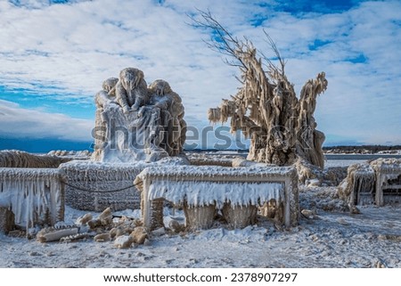 Strange Ice Formations on the monument, tree and benches on Pier in Lake Erie, Canada, Day after Winter Storm, stormy sky Royalty-Free Stock Photo #2378907297