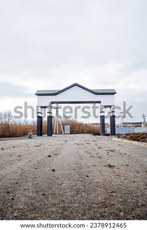 Entrance group arch in a suburban village, laying new asphalt, autumn in the village, entrance gate to an elite village. High quality photo