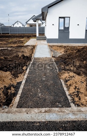 Pedestrian path to the house, suburban construction, asphalt on the road, concrete strip, pavement of the house, rack outside the city. High quality photo
