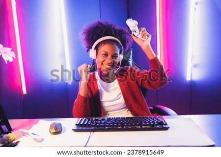 African American girl gaming streamer team winner playing online fighting with Esport wearing headphones in neon lighting room. Talking other players planing strategies to win competitors. Tastemaker. Royalty-Free Stock Photo #2378915649