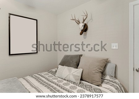 Modern Minimalistic Bedroom Interior with Neutral Tones, Geometric Patterned Bedspread, and Blank Framed Wall Art Mockup