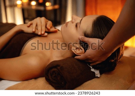 Caucasian woman enjoying relaxing anti-stress head massage and pampering facial beauty skin recreation leisure in warm candle lighting ambient salon spa in luxury resort or hotel. Quiescent Royalty-Free Stock Photo #2378926243