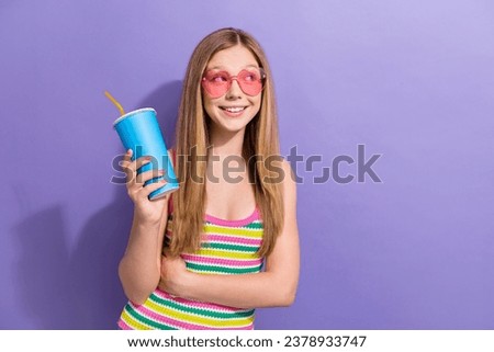 Photo portrait of cute teen blonde woman look empty space drink juice wear trendy striped clothes isolated on purple color background