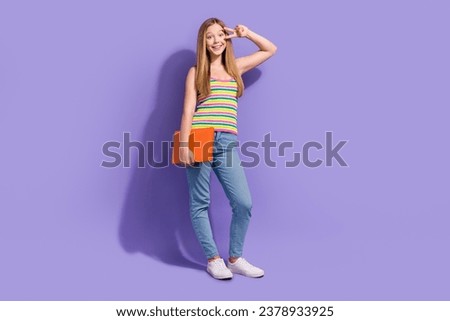 Full size photo of pretty teenager blonde girl hold laptop show v-sign hi wear trendy striped outfit isolated on purple color background