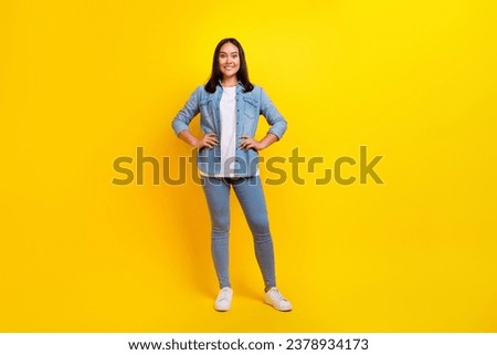 Full size photo of satisfied positive woman with straight hairdo dressed jeans shirt holding arms on waist isolated on yellow background