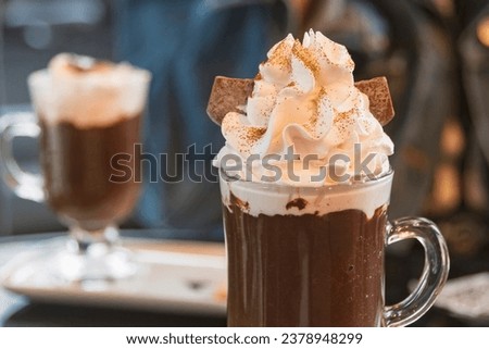 Hot chocolate with whipped cream and golden edible glitter in a transparent cup. Blurred background. Royalty-Free Stock Photo #2378948299