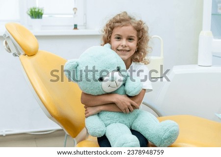 Happy little girl having dentist's appointment in modern clinic. Little patient, adorable little child girl sitting in dentist's chair during appointment in pediatric dentistry clinic Royalty-Free Stock Photo #2378948759