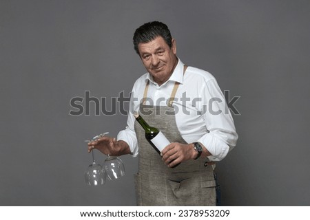 Mature man holding a bottle of red wine and two empty glasses Royalty-Free Stock Photo #2378953209