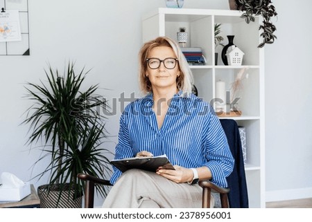 Professional Psychotherapy. Successful female Psychologist Smiling To Camera Sitting On armchair In Office. Mature 50s middle-aged professional portrait teacher, coach, mentor, therapist, counselor Royalty-Free Stock Photo #2378956001
