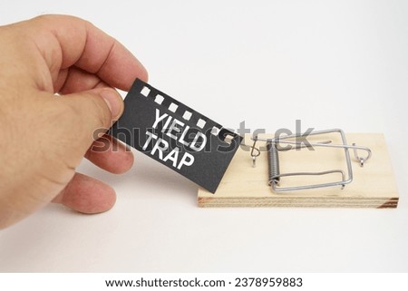 A man pulls the bait from a mousetrap. Bait, a sheet of black paper with the inscription - yield trap. Finance and law concept.