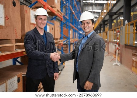 Two businessmen shaking hands in a warehouse It is a warehouse of spare parts and equipment for repairing machinery and passenger cars in the skytrain transportation system.